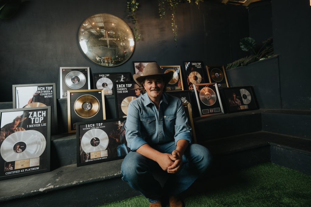 Zach Top, flanked by RIAA Platinum and Gold records. 
Photo Credit: Hunter Hart 